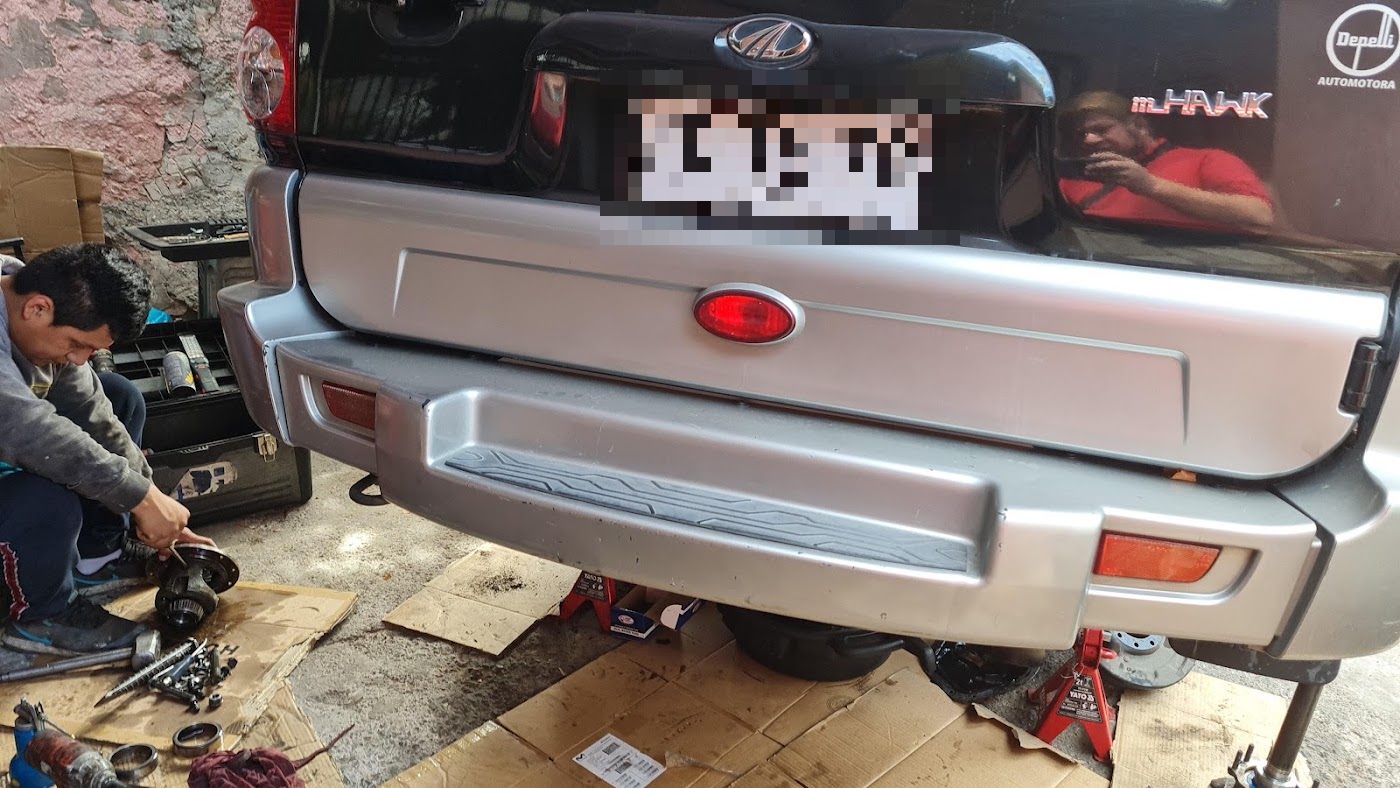 Camioneta Mahindra en reparación con un mecánico trabajando debajo